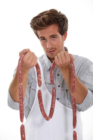 Yong man holding fresh sausagesの写真素材