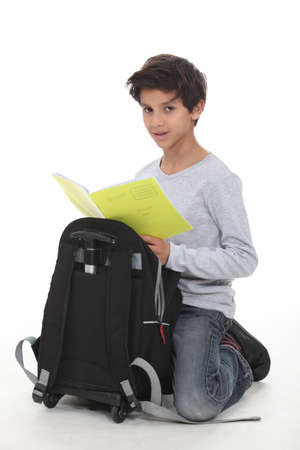 Schoolboy kneeling by backpackの写真素材