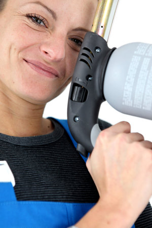 closeup portrait of young blonde female apprentice holding spot welderの写真素材