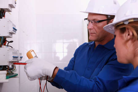 Electricians fitting a fuseboxの写真素材