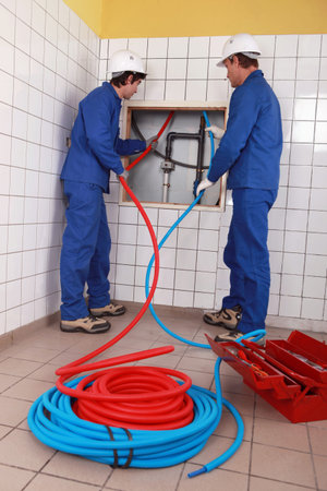 Plumbers installing new hot and cold pipes