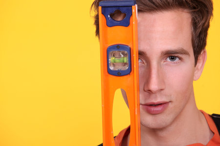 Carpenter covering his face with spirit-level
