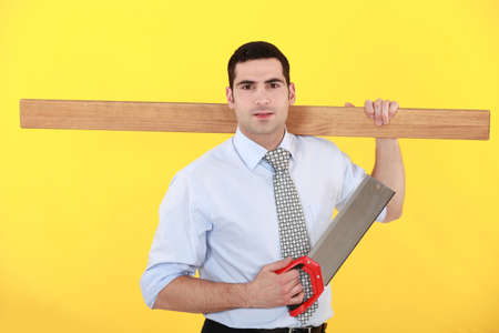 Businessman stood with saw and plankの写真素材