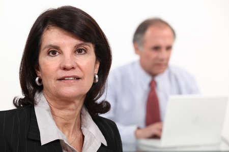 Mature businesswoman and man using a laptopの写真素材