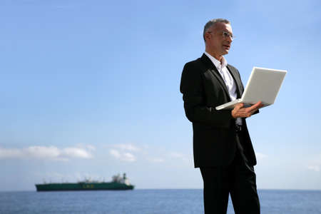 Businessman using his laptop by the water's edgeの写真素材