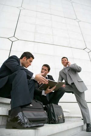 Businessmen sitting outside a city buildingの写真素材