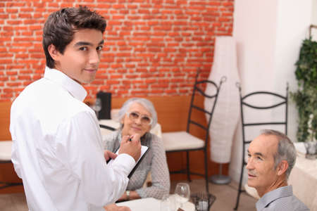 mature couple at restaurant with waiterの写真素材