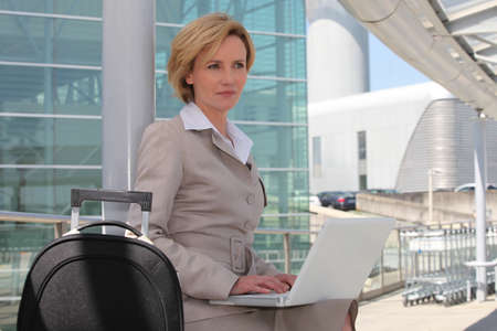 Businesswoman on laptop outside airportの写真素材