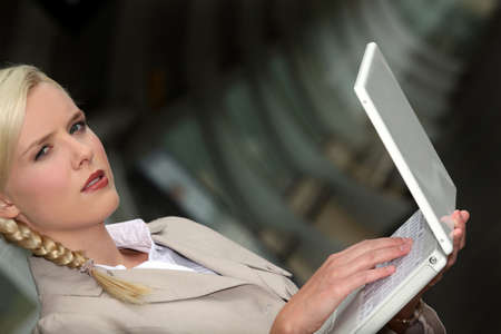 serious woman wearing a beige suit is working on her laptop in a dark tunnelの写真素材