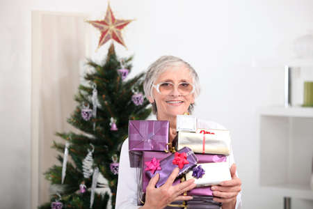 Old woman holding Christmas presentsの写真素材