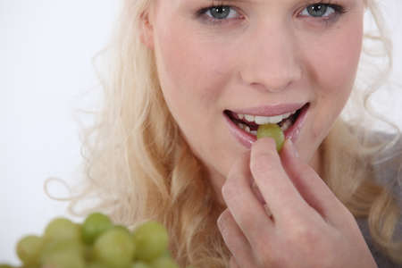 Woman eating green grapesの写真素材