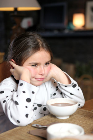 Grumpy little girl sat with hot chocolate