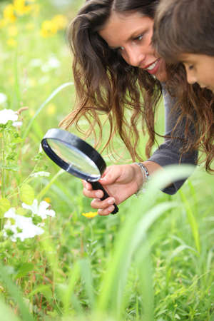 a woman and a little boy watching flowers with a magnifying glassの写真素材