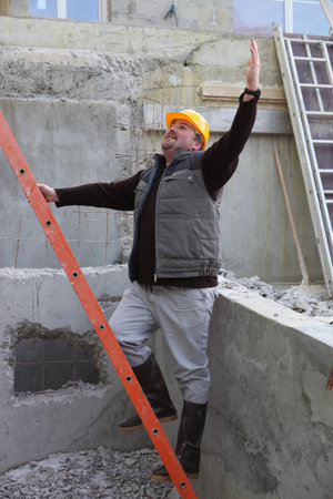 Builder stood by ladder waving