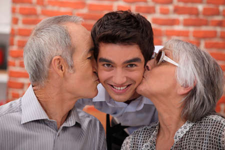 Grandparents kissing their adult grandsonの写真素材