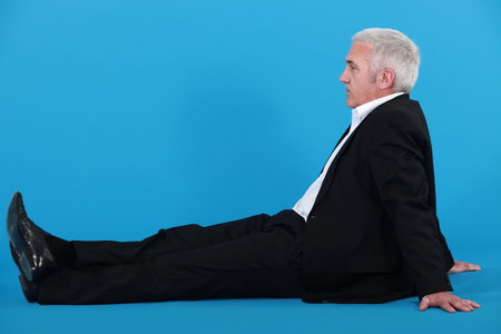 Profile of senior businessman sat on the floor