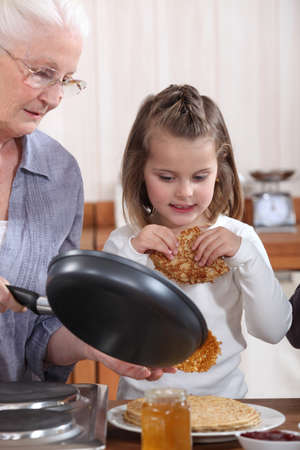 Grandmother and granddaughter making pancakesの写真素材
