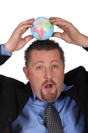 Businessman balancing a globe on his headの写真素材