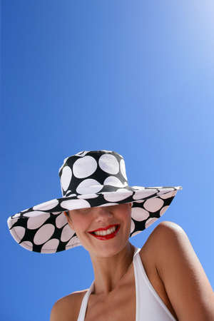 Brunette stood on a beach wearing swim wear and spotted hatの写真素材