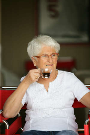 Elderly woman drinking a cup of coffeeの写真素材