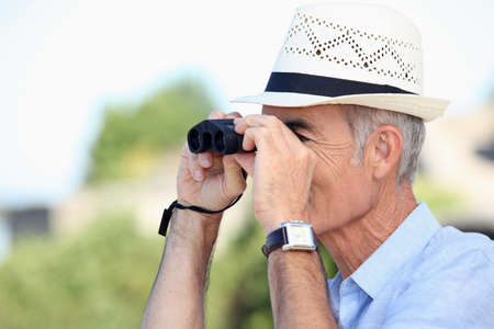 Old man looking through binocularsの写真素材