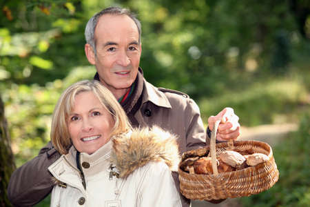 Couple gathering mushrooms in basketの写真素材