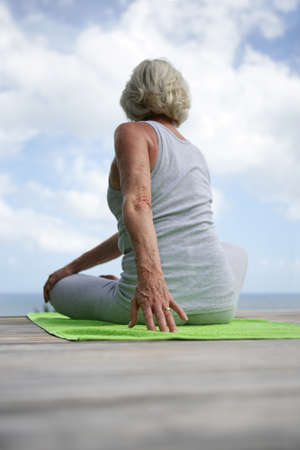Woman performing yoga moves on wooden jettyの写真素材
