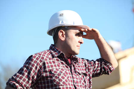 Tradesman shielding his eyes from the sunlightの写真素材