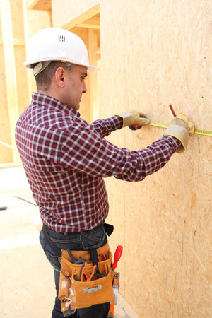 A carpenter taking measures onsite.
