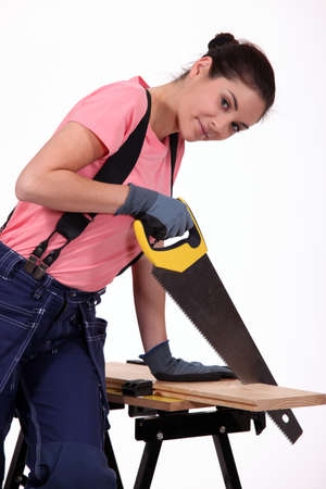 Young woman sawing a wooden boardの写真素材