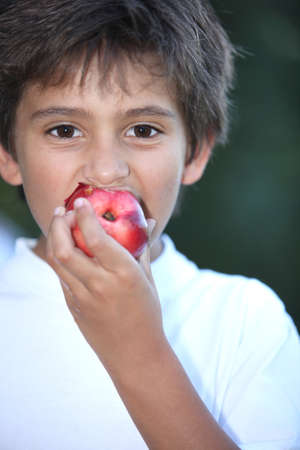 Young boy eating a nectarineの写真素材