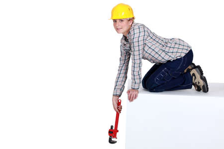 Woman reaching down with a wrenchの写真素材