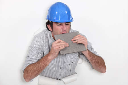 Fed-up tradesman biting a tileの写真素材