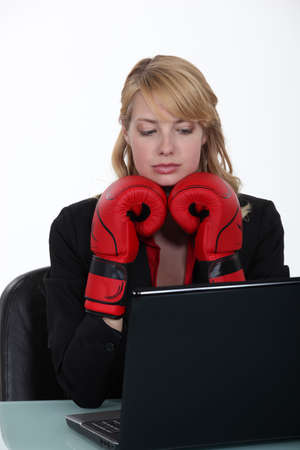 Businesswoman wearing boxing gloves and reading an e-mailの写真素材