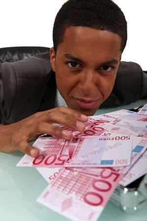 Young businessman with a pile of cashの写真素材