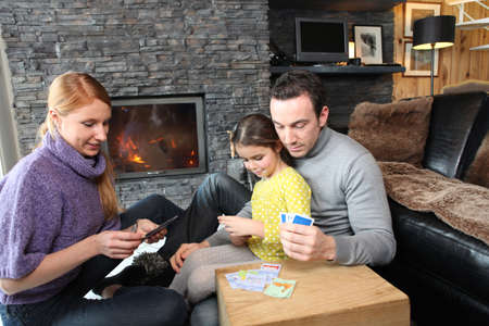 Family gathered by the fire place playing cardsの写真素材