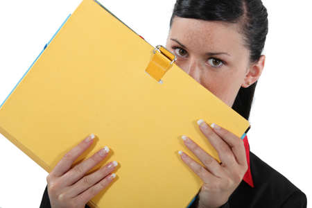 Businesswoman covering face with fileの写真素材