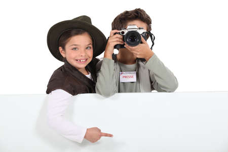 Child press photographers with a board left blank for your messageの写真素材