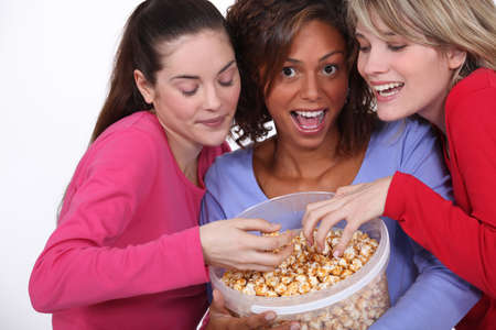 three young women eating popcornの写真素材