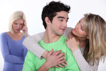 couple in love and jealous woman in backgroundの写真素材