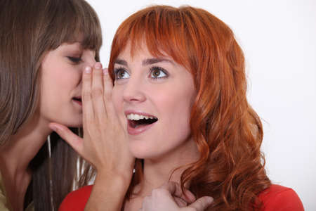 Woman whispering into another womanの写真素材