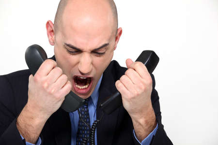 Bald man shouting into two telephonesの写真素材
