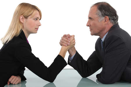 Businessman and woman arm wrestlingの写真素材