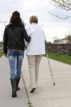 Young woman helping elderly lady walkの写真素材