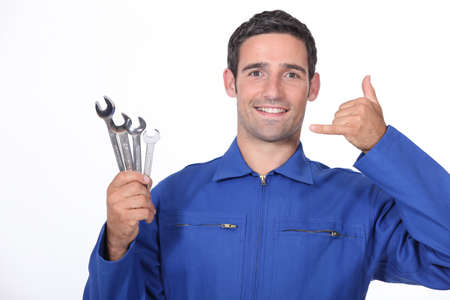 Man with spanners making a call me sign with his handの写真素材