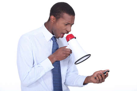 Man shouting through a megaphone at a cellphoneの写真素材