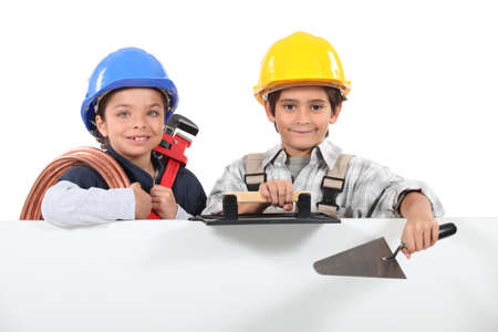 Children dressed as tradesman with a board left blank for your messageの写真素材