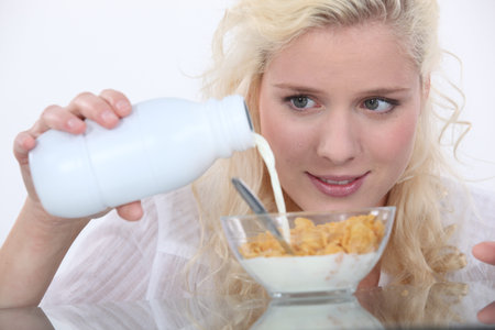Woman pouring milk into cereal bowl
