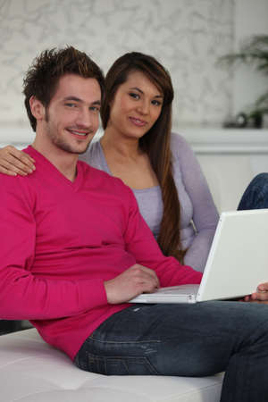 Attractive couple sitting on the sofa with laptopの写真素材