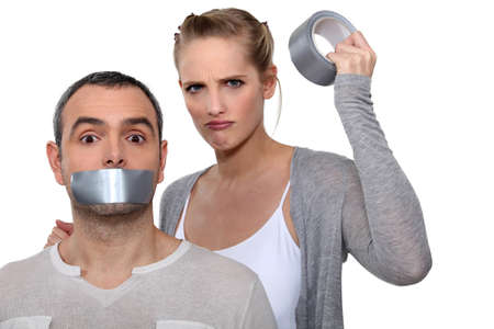 Woman taping boyfriends mouth closedの写真素材